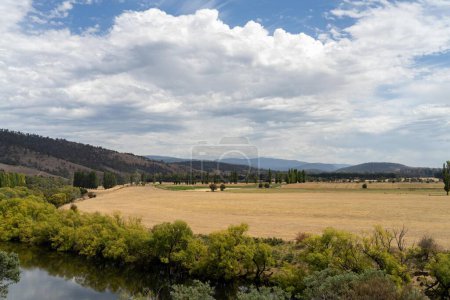 flowing river past farmland in summer, in the Tasmania wilderness. Lake with a Sandy beach and trees 