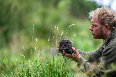 agricultor agrícola Sosteniendo tierra en una mano, sintiendo compost en un campo en Tasmania Australia. científico del suelo en Australia