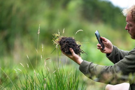 Landwirt sammelt Bodenproben in einem Reagenzglas auf einem Feld. Agronom überprüft Kohlenstoff im Boden und Pflanzengesundheit