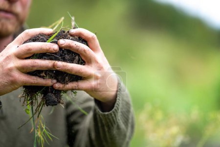 Landwirt hält Erde in der Hand und tastet Kompost auf einem Feld in Tasmanien Australien. bodenwissenschaftler in australien