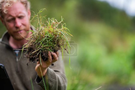 Científico australiano del suelo. agricultor orgánico regenerativo, tomando muestras de suelo y mirando el crecimiento de las plantas en una granja. practicar la sostenibilidad 