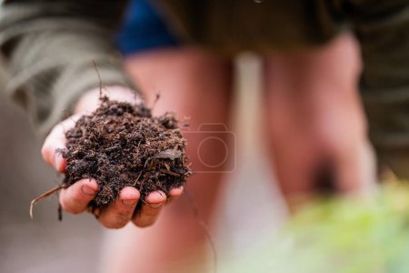 agricultor agrícola Sosteniendo tierra en una mano, sintiendo compost en un campo en Tasmania Australia. científico del suelo en Australia