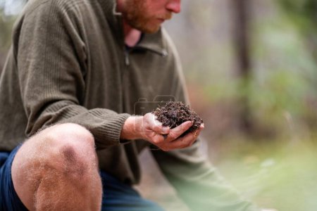 agricultural farmer Holding soil in a hand, feeling compost in a field in Tasmania Australia. soil scientist in australia