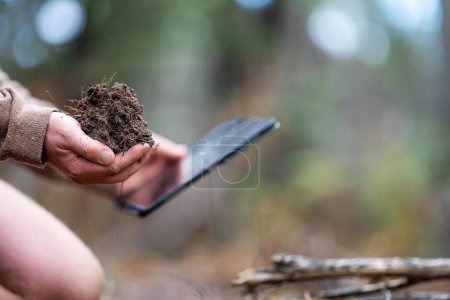 Foto de Estudiante universitario que realiza investigaciones sobre salud forestal. agricultor recogiendo muestras de suelo en un tubo de ensayo en un campo. Agrónomo verificando el carbono del suelo y la salud vegetal en una granja en Australia - Imagen libre de derechos