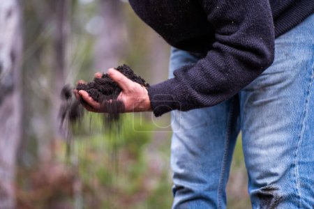 Sosteniendo tierra en una mano, sintiendo compost en un campo en Tasmania 
