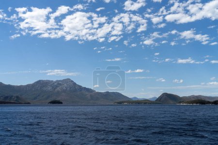 Yacht sailing on the horizon near the beach on the ocean ina  remote beautiful landscape, Tasmania, Australia 