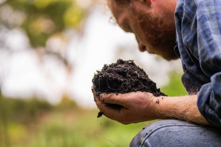 Regenerativer Biobauer, der Bodenproben entnimmt und sich das Pflanzenwachstum auf einem Bauernhof ansieht. Nachhaltige Landwirtschaft praktizieren