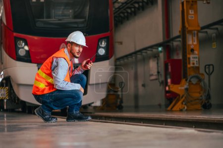 Téléchargez les photos : L'ingénieur est capturé dans l'environnement dynamique d'un train et d'un garage ferroviaire, immergé dans les tâches méticuleuses d'entretien, de réparation ou d'inspection.. - en image libre de droit