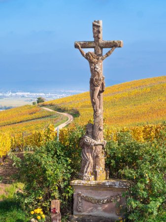 Christliches Kreuz zwischen Weinbergen in herbstlichen Farben auf dem Hügel von Turckheim - Weinstraße des Elsass, Frankreich.