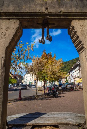 Photo for Thann, France - October 10, 2022: View through the frame of the medieval town fountain to the square of Thann in Alsace along the wine road - Royalty Free Image