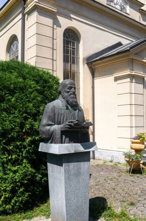 Foto de Lendava, Eslovenia - 15 de julio de 2023: Una estatua de Primoz Trubar, un predicador protestante y considerado el fundador de la literatura eslovena, así como la Iglesia Evangélica en Eslovenia. - Imagen libre de derechos