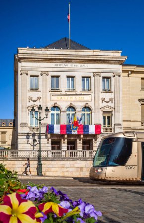Foto de Orleans, Francia - 10 de agosto de 2023: Ayuntamiento histórico de Orleans con tranvía y flores en primer plano - Imagen libre de derechos