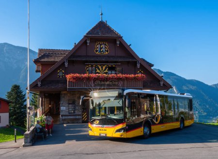 Foto de Seelisberg, Suiza - 6 de septiembre de 2023: Un autobús suizo frente al pintoresco edificio de madera de la estación superior del funicular Treib-Seelisberg - Imagen libre de derechos