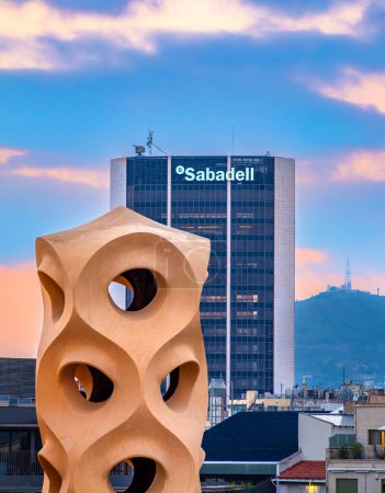 Téléchargez les photos : Barcelone, Espagne - 7 octobre 2023 : Siège de la banque Sabadell à Barcelone, Catalogne, Espagne. Une sculpture sur le toit de la maison Pedrera au premier plan - en image libre de droit