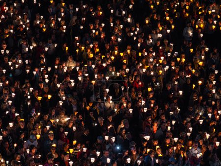 Foto de Lourdes, Francia - 12 de octubre de 2023: Una multitud de peregrinos con velas encendidas rezando en una procesión de peregrinación nocturna en Lourdes. - Imagen libre de derechos