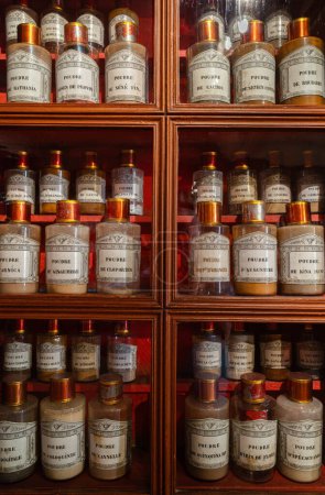 Foto de Beaune, Francia - 16 de agosto de 2023: Farmacia gabinete de madera del histórico hospital de Beaune - ingredientes para la preparación de medicamentos. Botellas en el estante en farmacias antiguas. Fondo médico vintage. - Imagen libre de derechos