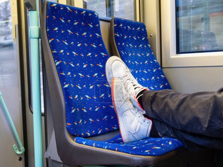 Eine unhöfliche und ungebildete junge Person setzte ihre Füße auf den Sitz einer öffentlichen Straßenbahn