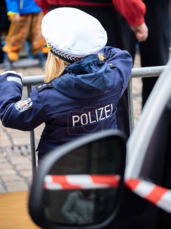 Téléchargez les photos : Une mascarade. Une fille en costume de carnaval, un uniforme de police avec une pancarte de police allemande. Traduire en anglais : Police. - en image libre de droit