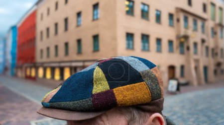 Una colorida gorra multicolor en la cabeza de un hombre desconocido con un fondo borroso de la antigua ciudad de Wasserburg am Inn