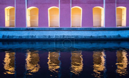 Beleuchteter Fußweg entlang der Memminger Ach in Memmingen und die Spiegelung der Architektur im Wasser