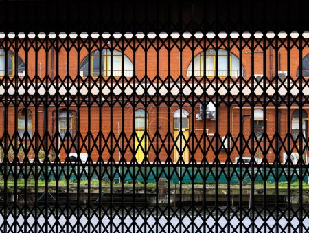 Téléchargez les photos : Londres, Royaume-Uni - 26 février 2024 : Vue à travers une clôture métallique d'un bâtiment industriel avec une façade orange - en image libre de droit