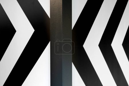 Abstract motif of black arrows from left and right on a white background pointing towards the central pillar
