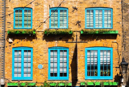 Téléchargez les photos : Londres, Royaume-Uni - 29 avril 2024 : Façade orange avec fenêtres bleues à Neal's Yard, une ruelle colorée et dynamique dans le quartier de Covent Garden à Londres. Maison de Monty Python - en image libre de droit