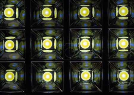 Ein modernes und abstraktes Foto, das ein Gitter aus Glaswürfeln mit leuchtenden LED-Lichtern zeigt und ein fesselndes Licht- und Schattenspiel in Blau und Schwarz erzeugt.
