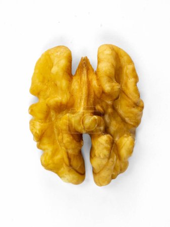 Un primer plano de un grano de nuez marrón dorado, partido por la mitad, parecido a un cerebro, mostrando texturas intrincadas e imperfecciones naturales sobre un fondo blanco.