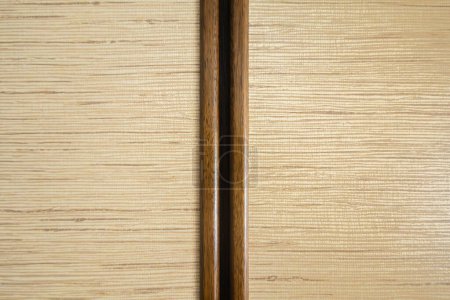 Un panel de madera de color claro con patrón de grano horizontal, dividido por una franja vertical más oscura. Diseño limpio y sencillo con textura de madera natural.