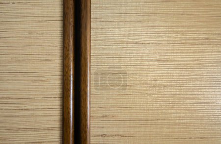 Un panel de madera de color claro con patrón de grano horizontal, dividido por una franja vertical más oscura. Diseño limpio y sencillo con textura de madera natural.