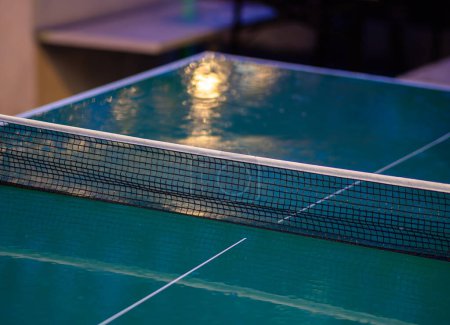 Photo for Zurich, Switzerland - May 16, 2024: Close-up of wet green ping pong table with white boundary stripe and mesh net in an outdoor recreational space, rainy night - Royalty Free Image