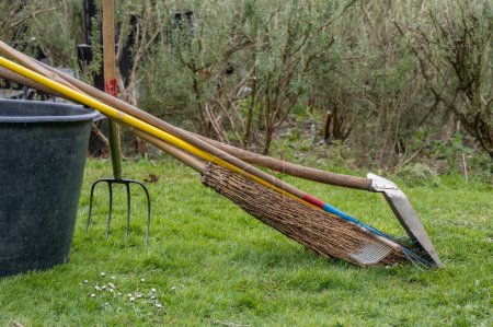 Gardening tools. Broom, shovel and rake on flowerpot in the garden. Outdoors.