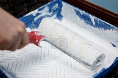 barbouiller rouleau de peinture dans le seau avec raclette avant de peindre mur