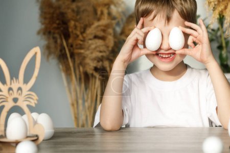Foto de A cheerful child closes his eyes with eggs that he has prepared for the Easter holiday, symbols of the holiday for creativity - Imagen libre de derechos