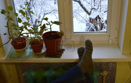 Photo for Feet in wool socks on a warm radiator in winter. - Royalty Free Image