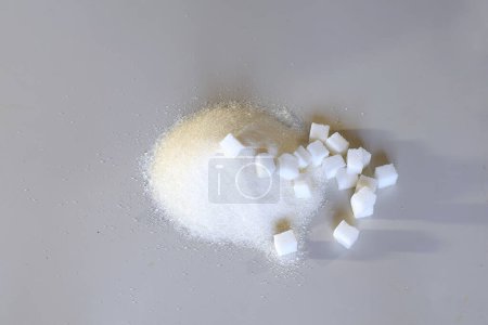 Refined sugar and granulated sugar on a gray table.