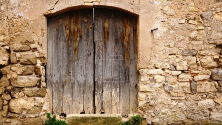 Photo for Old wooden door in worn rustic facade - Royalty Free Image