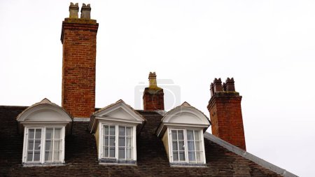 Foto de Ventanas y chimeneas en el techo casa de estilo británico contra el cielo - Imagen libre de derechos