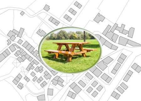 Photo for Wooden picnic table on a green meadow of a public park against an imaginary city map with recreation areas for leisure activities and municipal services - Royalty Free Image