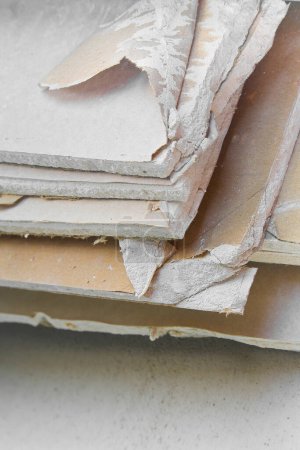 Foto de Demolished plasterboard wall, made of plaster and cardboard, with fragments of material and dust in a construction site - Imagen libre de derechos