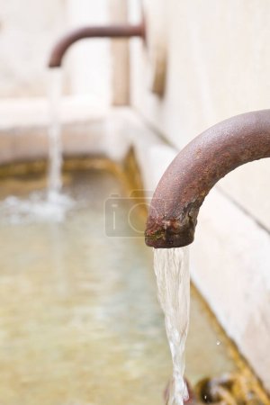 Téléchargez les photos : Eau provenant d'une vieille fontaine italienne avec tube rouillé - en image libre de droit