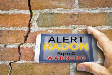 Foto de Dispositivo de información portátil para monitorear el radón de gas radiactivo - imagen conceptual de prueba de radón contra una pared agrietada. - Imagen libre de derechos