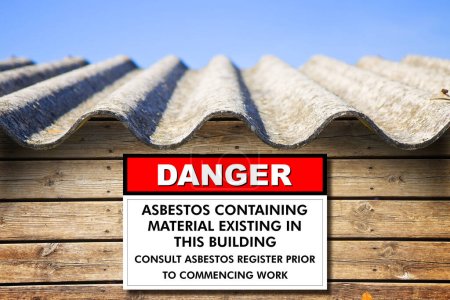 Foto de Old aged dangerous asbestos roof - concept with placard indicating danger - Imagen libre de derechos