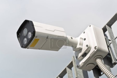 Téléchargez les photos : Caméra de sécurité contre une grille métallique pour le contrôle de sécurité des espaces urbains - en image libre de droit