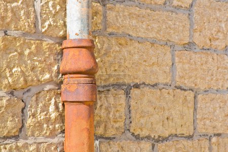Foto de Antiguo tubo descendente de hierro fundido y cobre contra una pared de piedra - Imagen libre de derechos