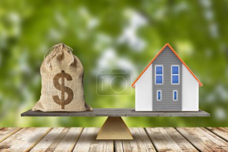Real estate balance concept with dollars and home model - Building activity and construction industry costs concept
