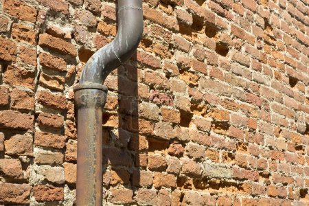 Téléchargez les photos : Vieille descente rouillée en cuivre et fonte contre un mur de briques - en image libre de droit