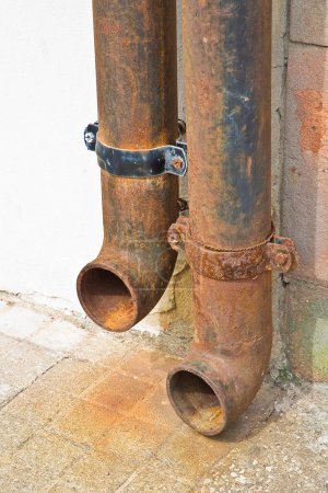 Foto de Viejo tubo de hierro fundido oxidado contra una pared. - Imagen libre de derechos