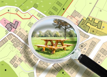 Photo for Wooden picnic table on a green meadow of a public park against an imaginary city map and General Urban Plan with recreation areas, green spaces for leisure activities and municipal service - Royalty Free Image